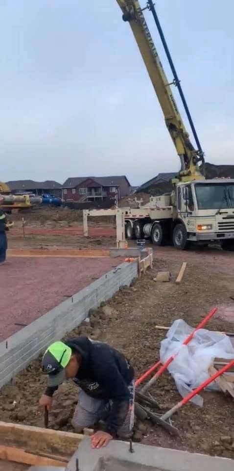 A boom pump truck set up on its outriggers to place concrete into the forms
