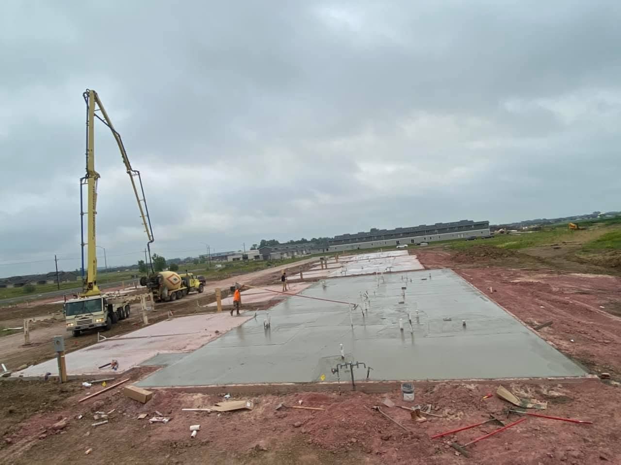 A boom pump placing concrete on a large new-construction slab