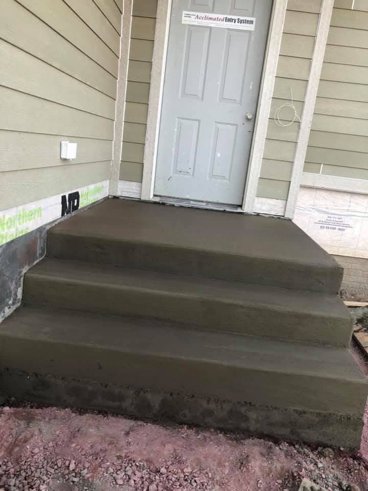 Freshly finished concrete steps leading up to the entrance of a new home