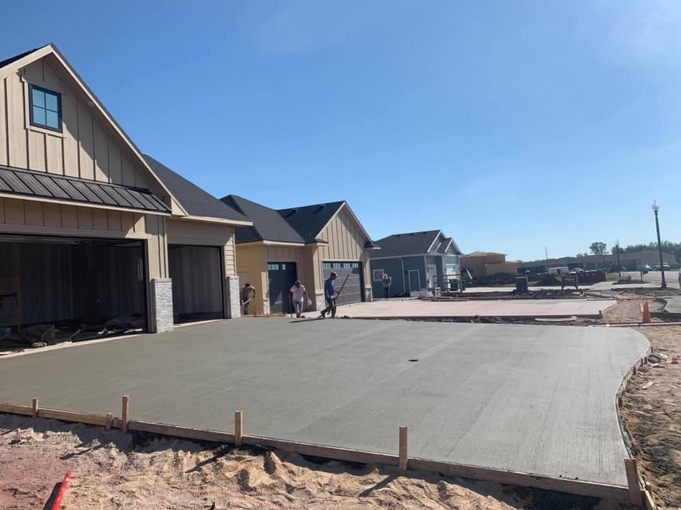 A broad finished concrete driveway in front of a new home, with formed edges