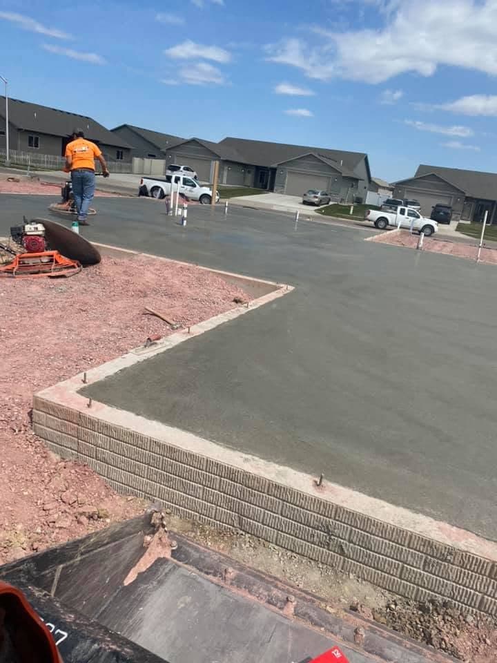 A fresh driveway apron being power-troweled, edged with a brick-paver border