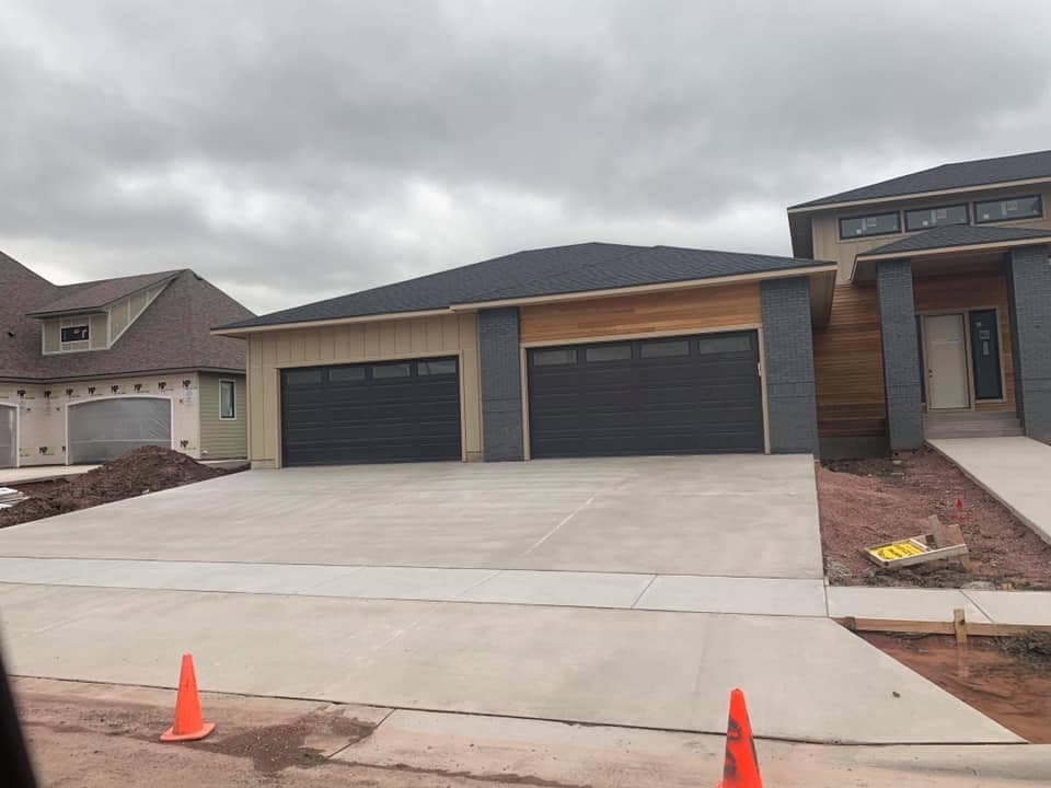 A finished three-car concrete driveway in front of a two-garage home