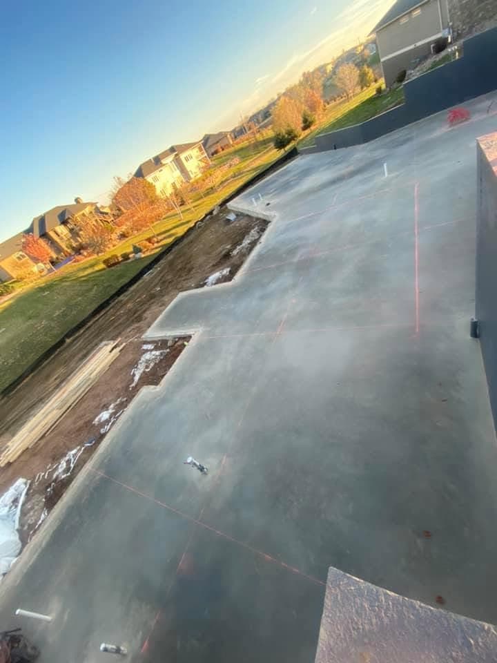 A large freshly finished slab caught at golden hour, chalk lines snapped across it and finished homes beyond