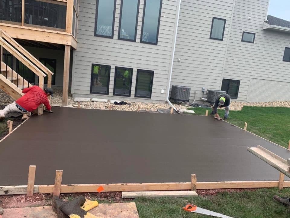 A finished patio slab against a modern home as our crew edges and trowels the perimeter
