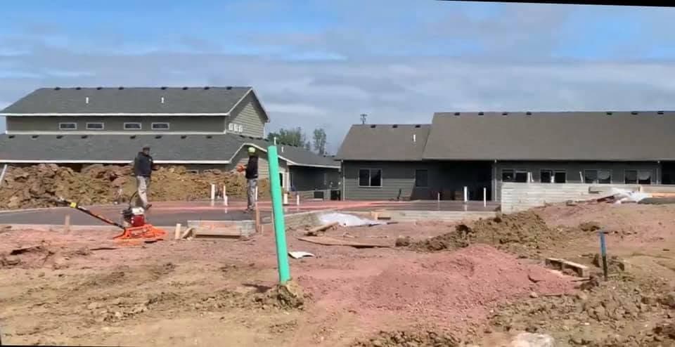 Wood forms laid out for a foundation with a plumbing rough-in standing up before the pour