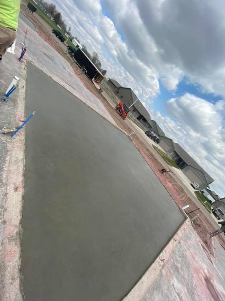 A large finished slab with a power trowel resting on it under a bright blue sky