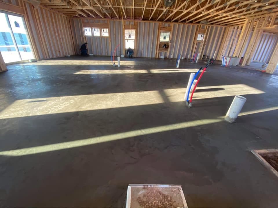 A finished concrete shop floor with plumbing stub-ups standing up as our crew frames the walls around it