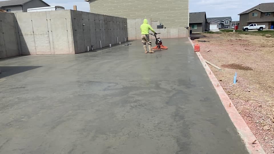 One of our crew power-troweling a fresh garage slab against a poured foundation wall