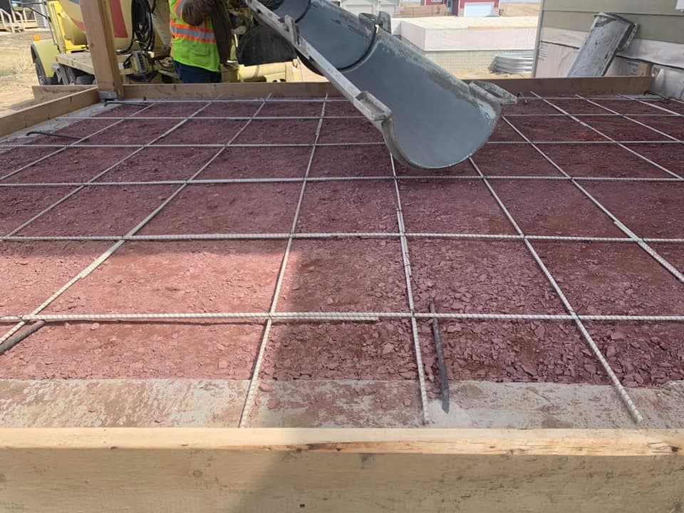 Steel reinforcing mesh laid over the base as concrete is placed from the chute