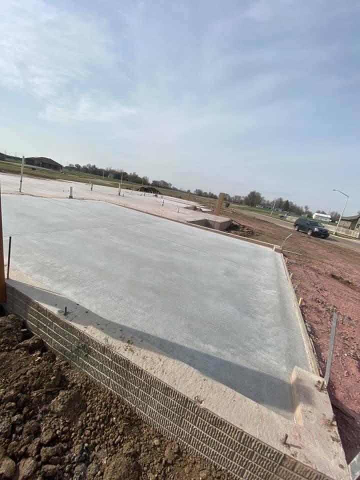 A broad broom-finished flatwork slab with a formed edge in the foreground