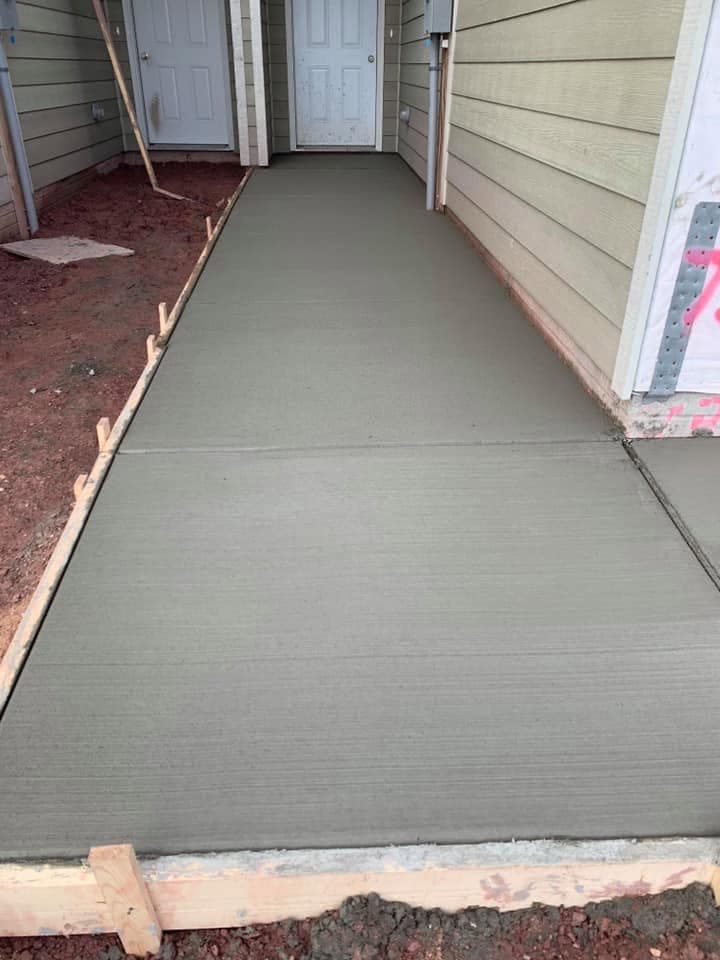 A finished concrete walkway poured along the side of a home, with formed edges