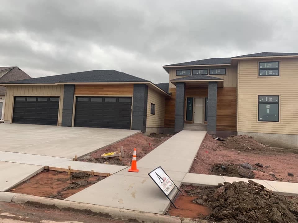 A straight concrete walkway leading from the driveway to the front entrance of a modern home